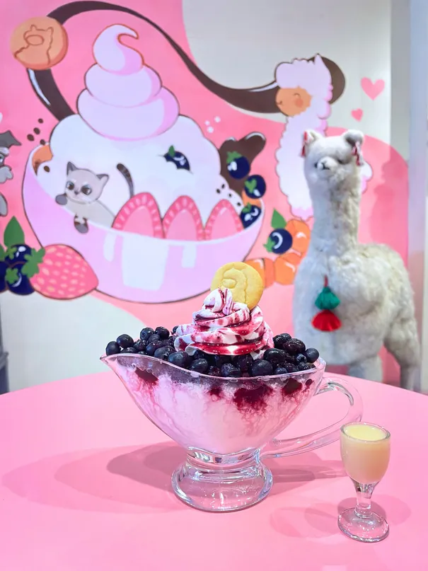 Fruto Rojo Bingsu servido en copa, con el mural de alpacas del local detrás